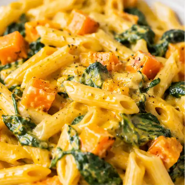 Nahaufnahme von cremiger One-Pot-Kürbis-Pasta mit Spinat, Hokkaido und Parmesan